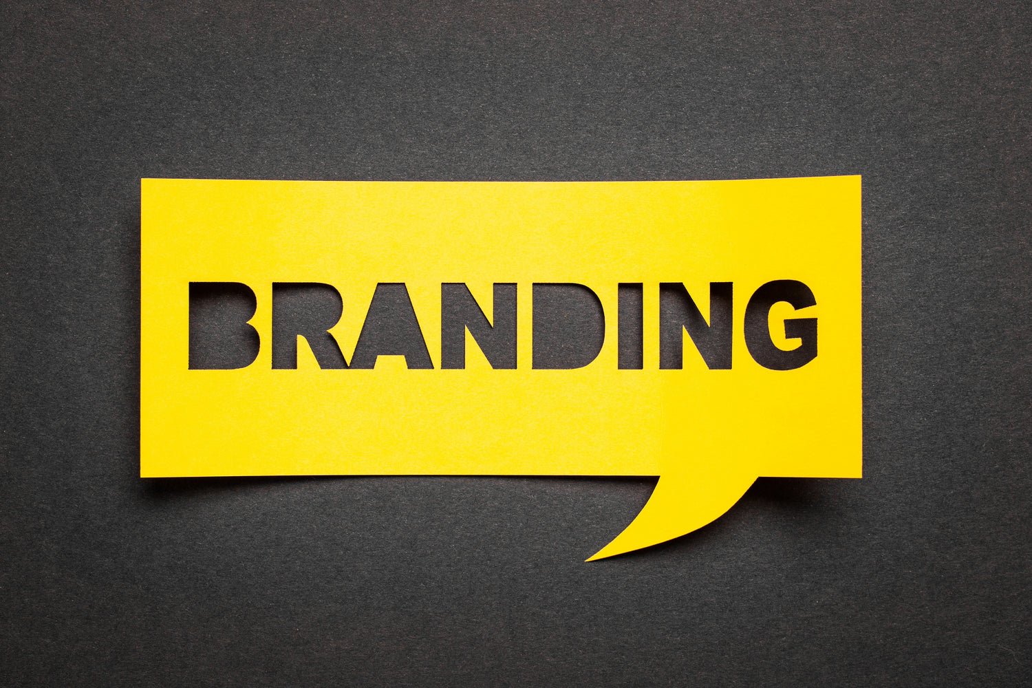 The word "BRANDING" cut out from a yellow speech bubble on a black background